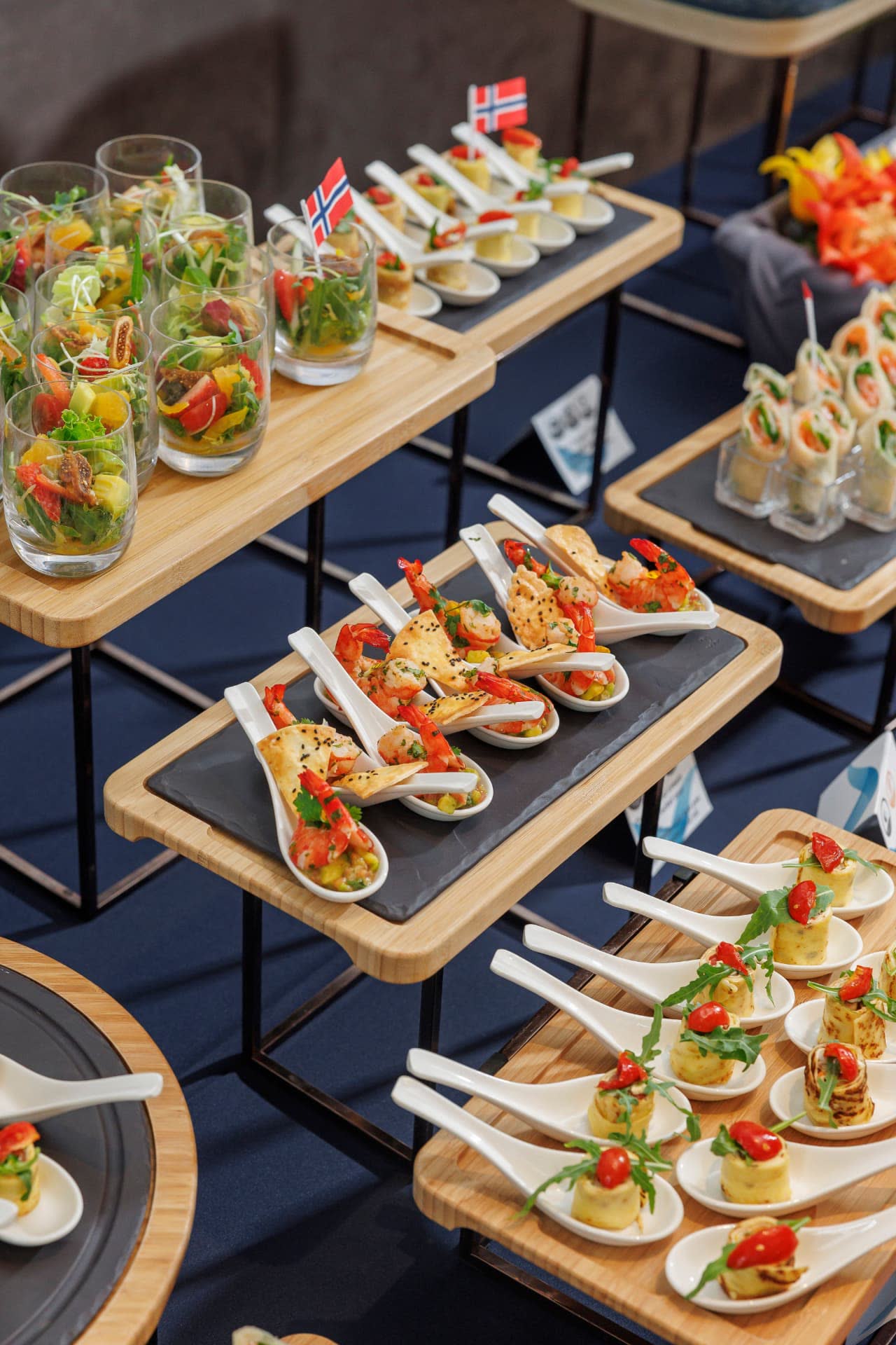 Shrimp canapés on porcelain spoons and salad verrines on tiered bamboo stands