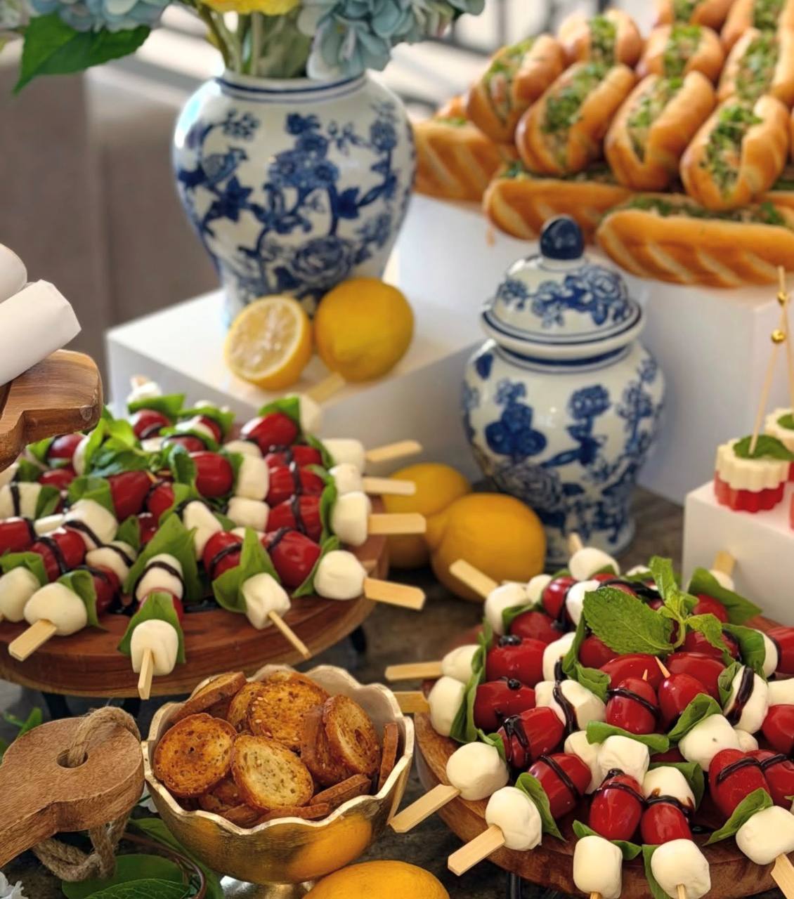 Caprese skewers with balsamic drizzle beside lemonade and blue-and-white porcelain