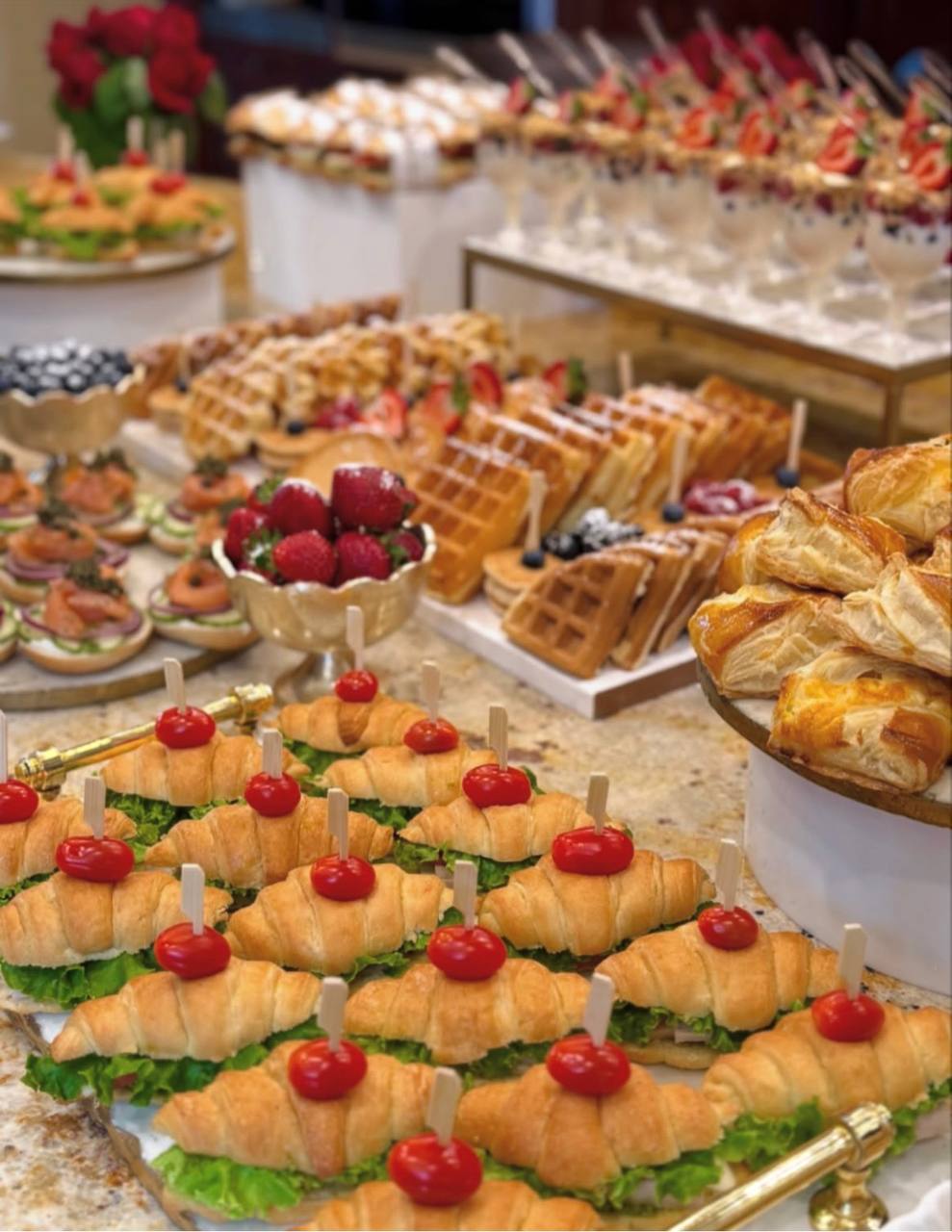 Brunch spread of croissant sandwiches, golden waffles, fresh berries and parfait cups