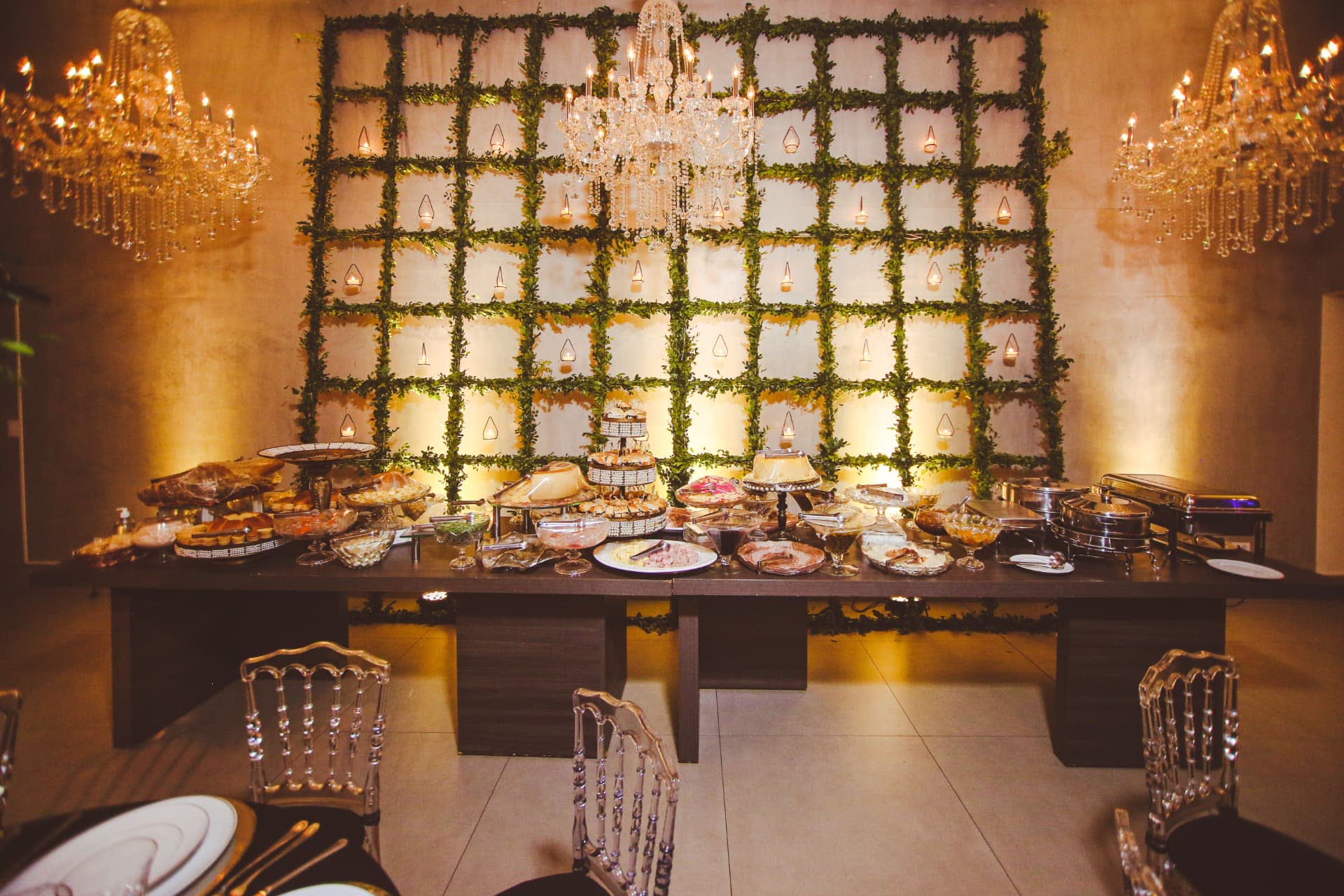 Candlelit buffet beneath crystal chandeliers and a living greenery wall